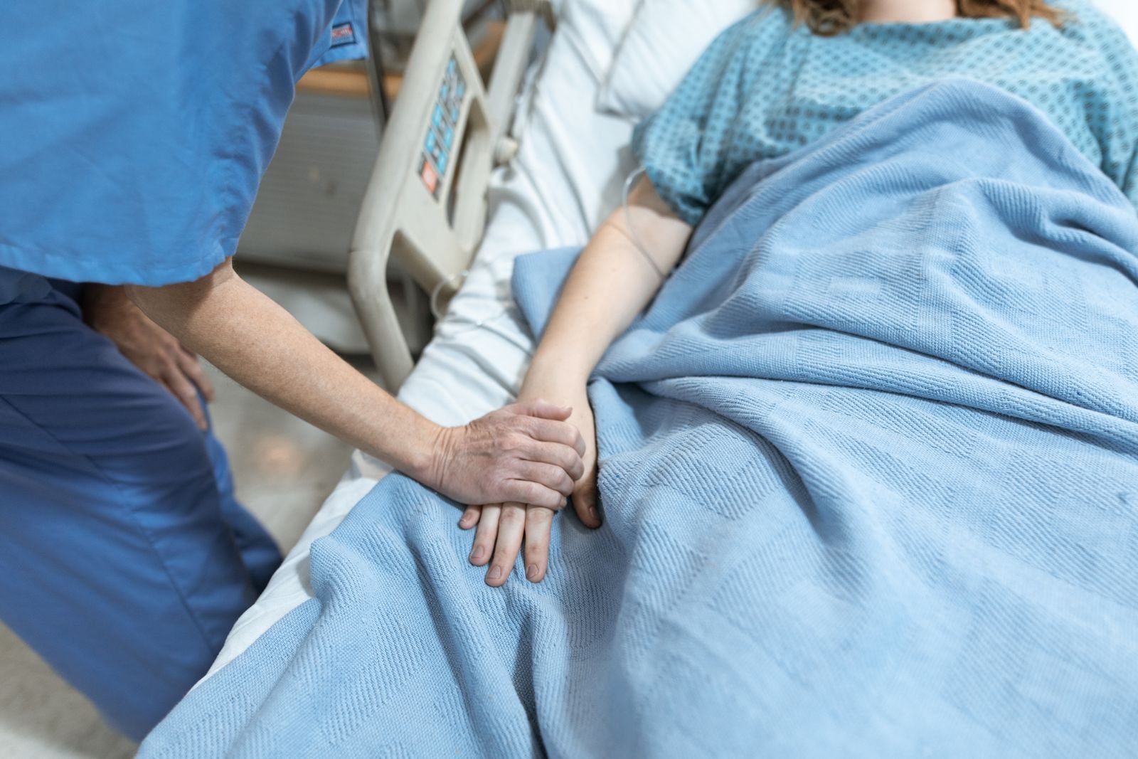 Profissional de saúde segurando a mão de paciente em cuidado hospitalar