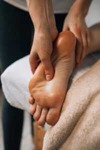 Mãos massageando a sola do pé, contexto de alívio da dor causada pela fascite plantar