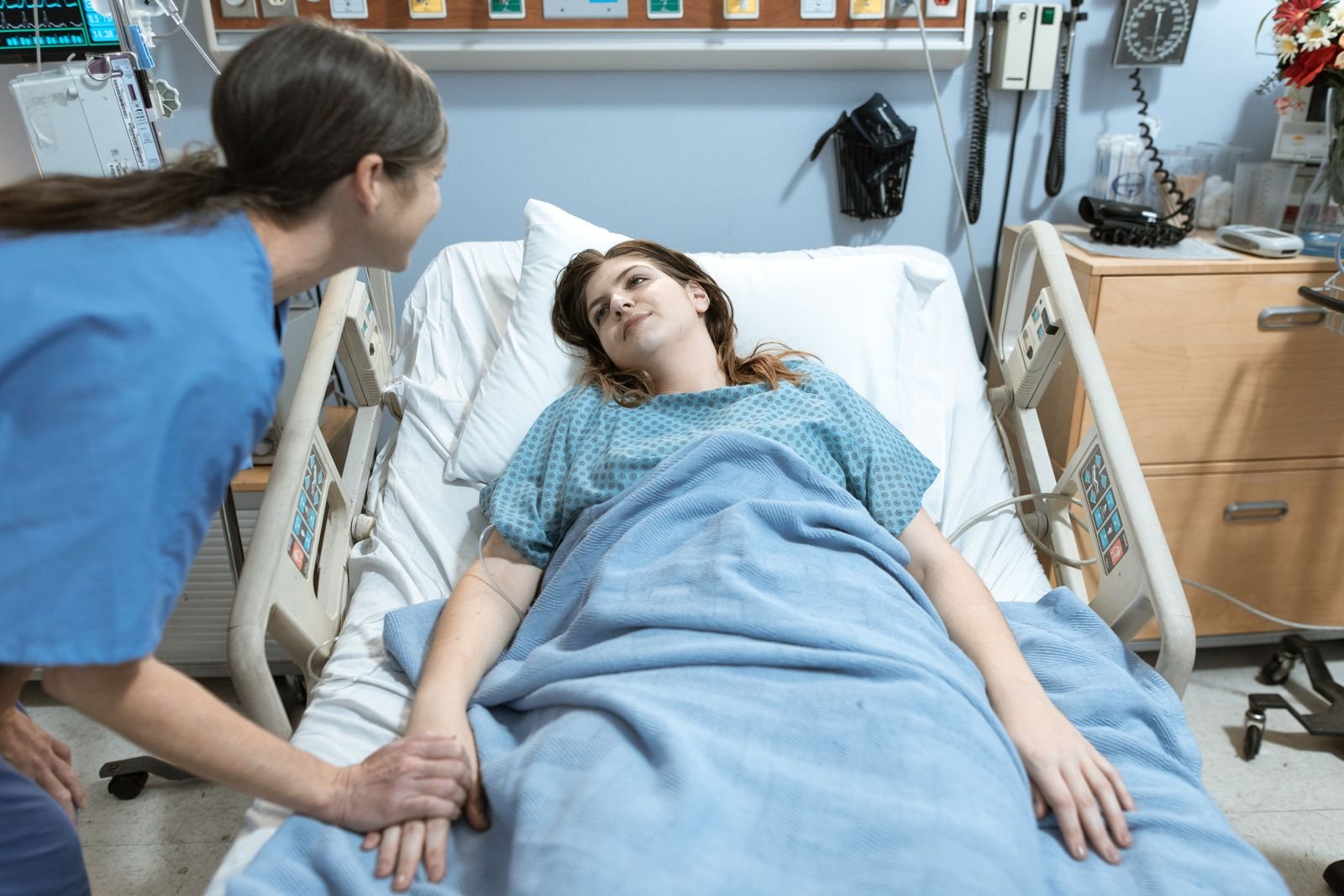 Enfermeira conversando com paciente em leito hospitalar, oferecendo apoio nos cuidados de saude