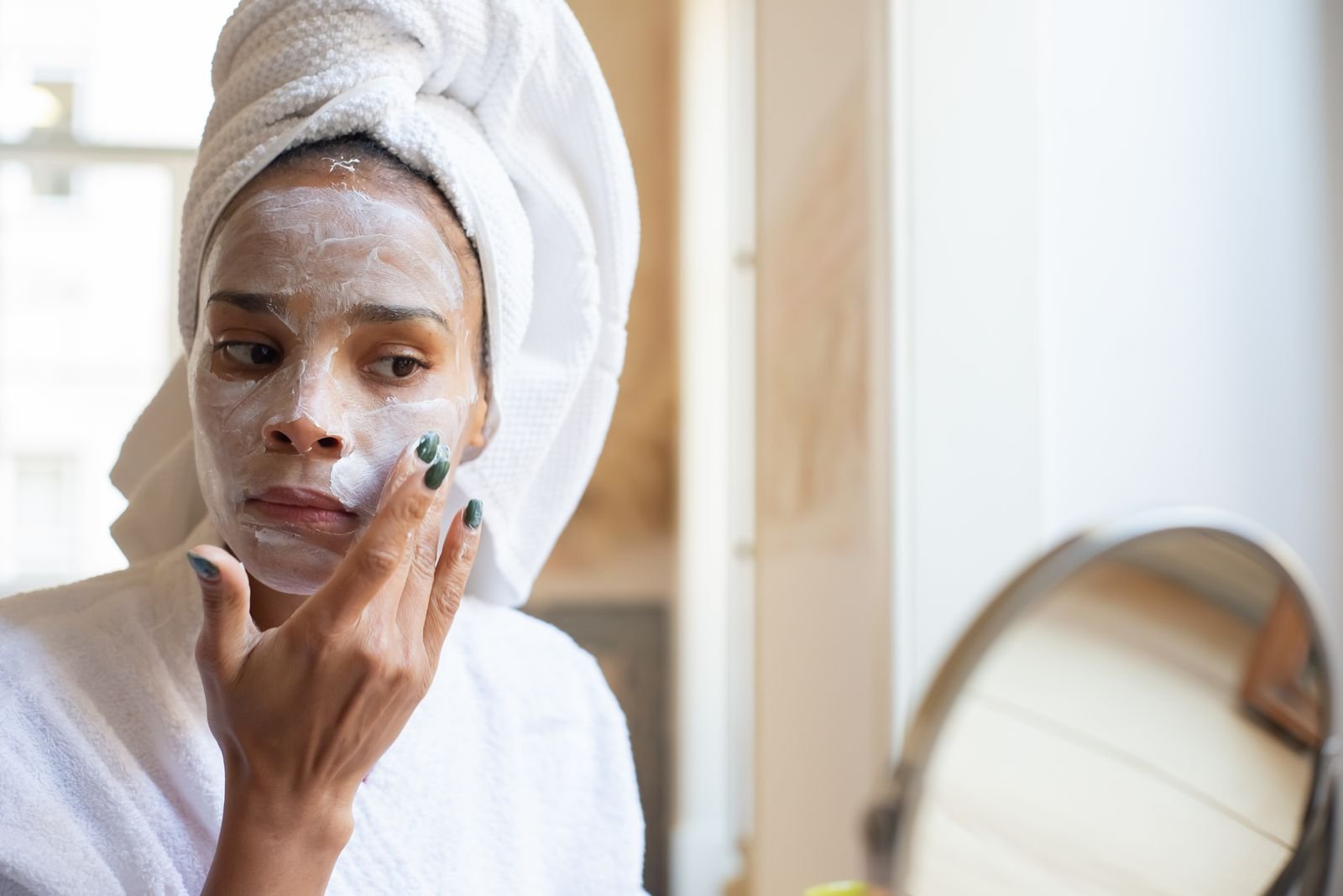 Mulher aplicando creme hidratante no rosto durante rotina de cuidados com a pele sensível