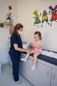 Pediatra examinando crianca pequena em consultorio infantil