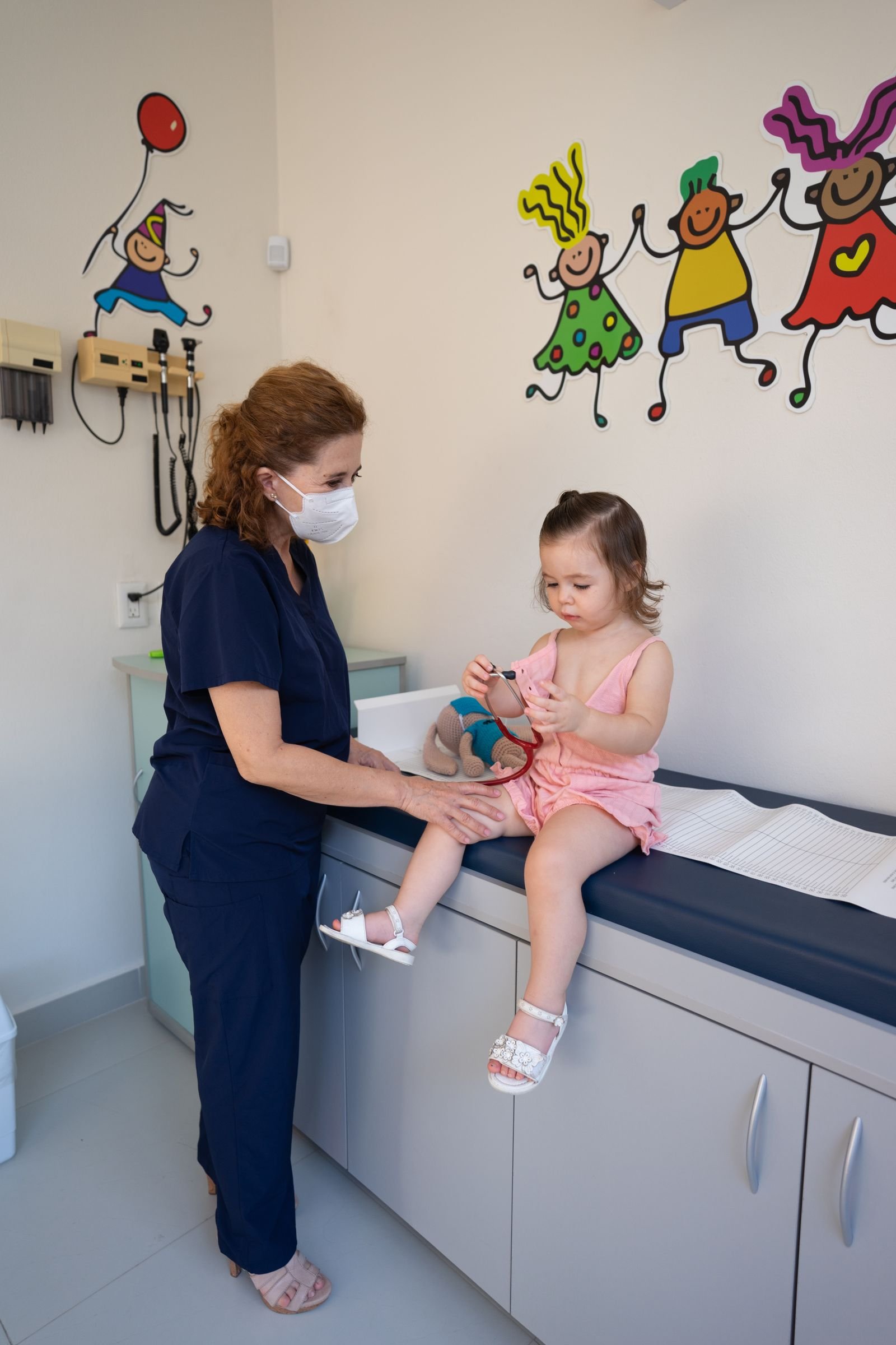 Pediatra examinando crianca pequena em consultorio infantil