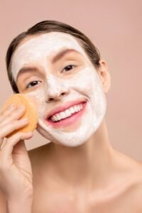 Mulher fazendo a limpeza facial do rosto, ilustrando a rotina de cuidados para pele oleosa e com tendência a acne