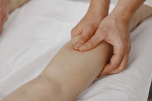 Profissional realizando massagem terapêutica na perna para estimular a circulação, relacionado ao cuidado com úlceras venosas